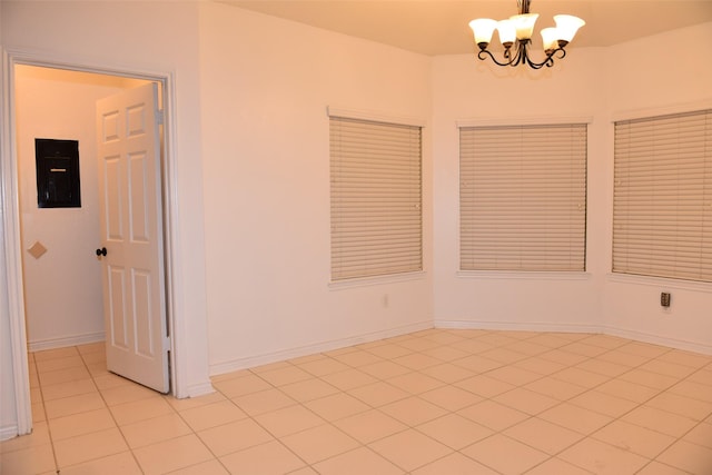 empty room with a notable chandelier, light tile patterned floors, and electric panel