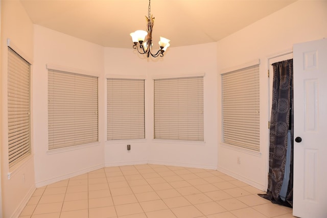 empty room featuring an inviting chandelier and light tile patterned floors