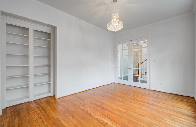 unfurnished room featuring an inviting chandelier, ornamental molding, french doors, and light wood-type flooring