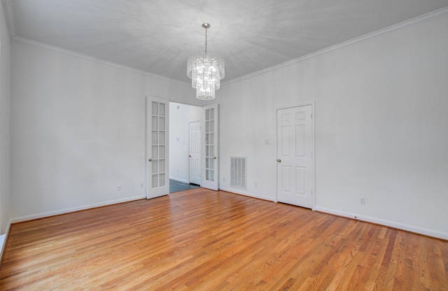 spare room featuring ornamental molding, french doors, a chandelier, and light wood-type flooring