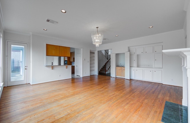 unfurnished living room featuring an inviting chandelier, crown molding, and light wood-type flooring