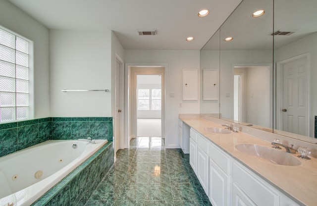 bathroom with vanity and tiled tub