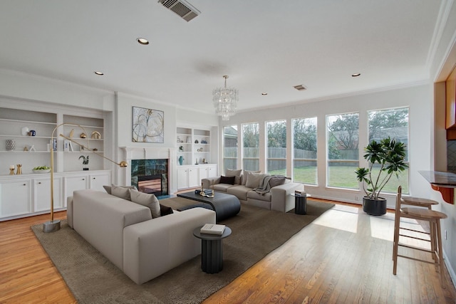 living room featuring crown molding, a premium fireplace, and light hardwood / wood-style flooring