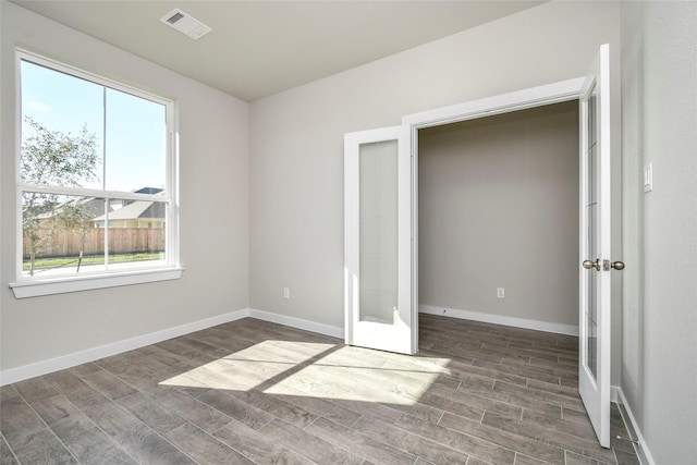 unfurnished bedroom featuring dark hardwood / wood-style flooring and french doors