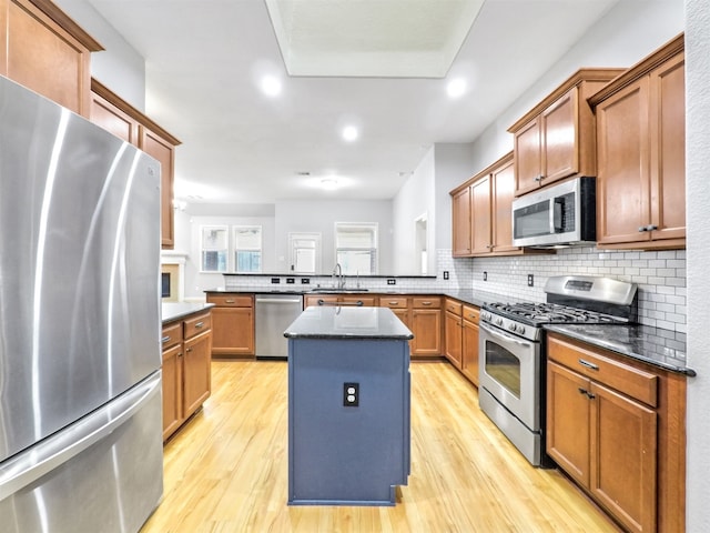 kitchen with sink, kitchen peninsula, a kitchen island, stainless steel appliances, and light hardwood / wood-style floors