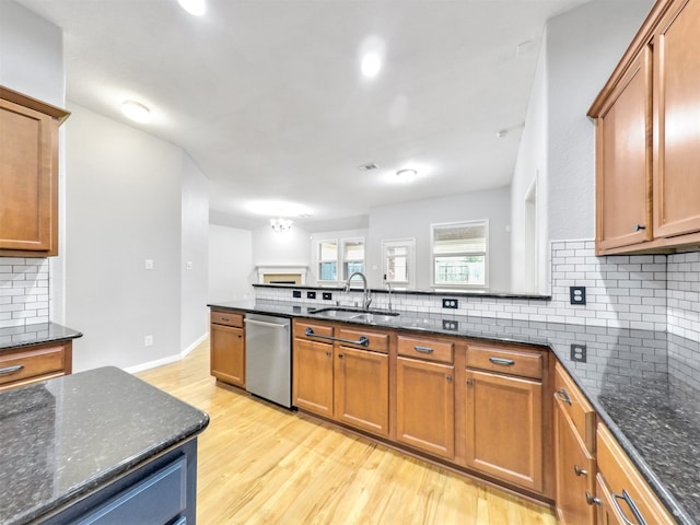 kitchen featuring sink, light hardwood / wood-style flooring, dishwasher, tasteful backsplash, and dark stone counters