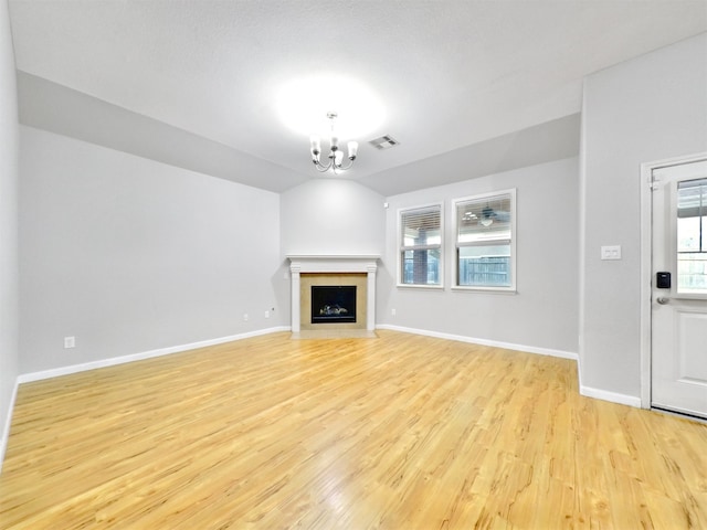 unfurnished living room featuring lofted ceiling, light wood-type flooring, and a chandelier