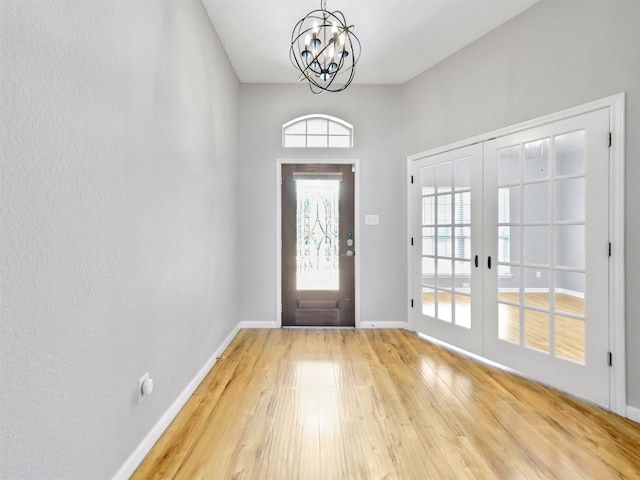 foyer with hardwood / wood-style floors, a notable chandelier, and french doors