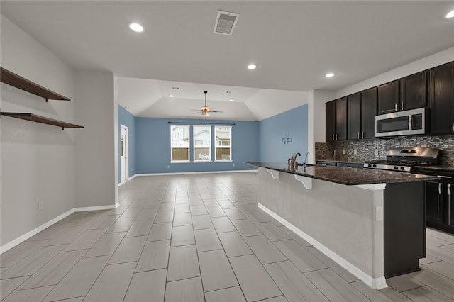 kitchen with tasteful backsplash, stainless steel appliances, a kitchen bar, and a kitchen island with sink