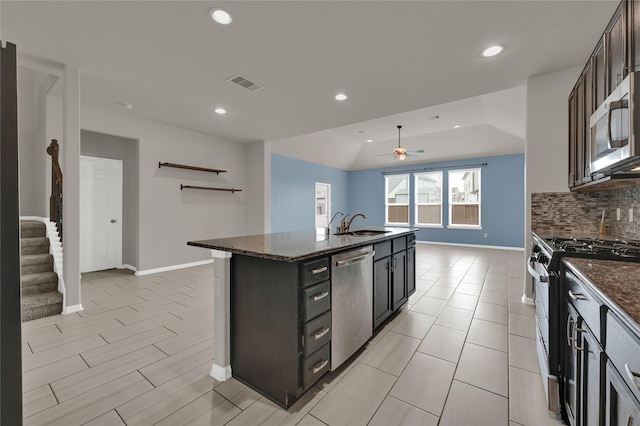 kitchen with lofted ceiling, sink, a center island with sink, stainless steel appliances, and decorative backsplash