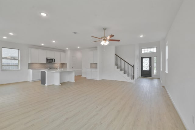 unfurnished living room with ceiling fan and light hardwood / wood-style floors