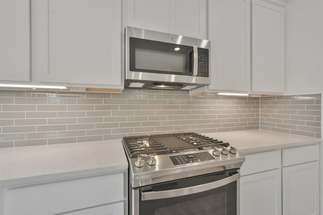 kitchen featuring light stone counters, decorative backsplash, white cabinets, and appliances with stainless steel finishes