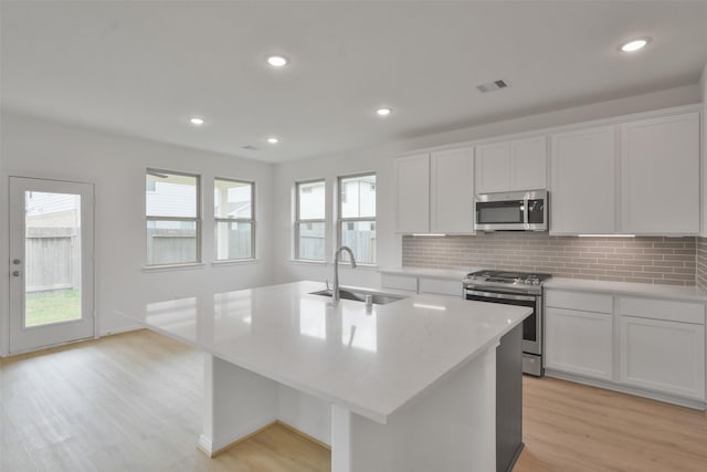 kitchen featuring stainless steel appliances, sink, a center island with sink, and white cabinets