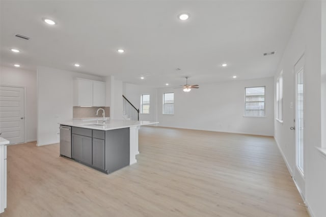 kitchen featuring tasteful backsplash, white cabinetry, an island with sink, sink, and stainless steel dishwasher