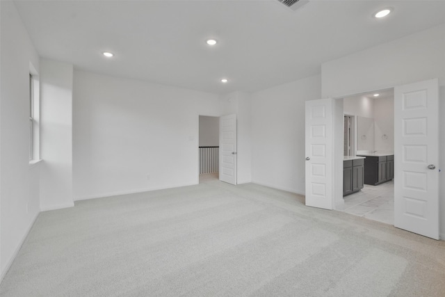 unfurnished bedroom with light colored carpet and ensuite bath