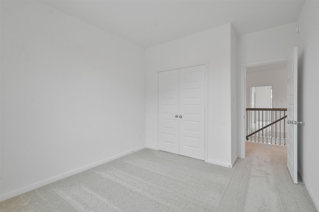 unfurnished bedroom featuring light colored carpet and a closet