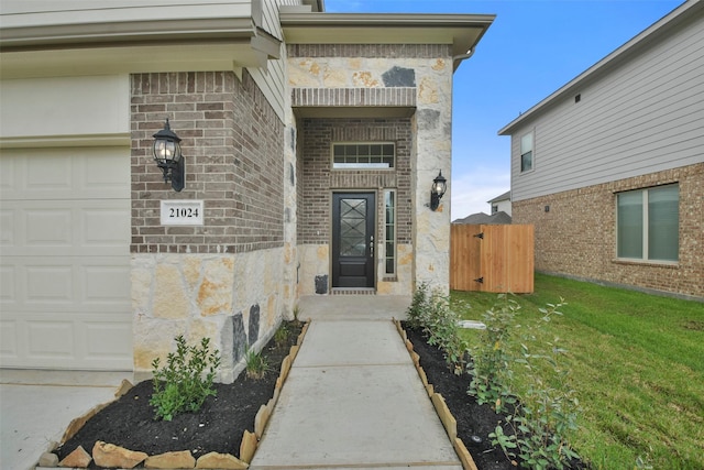 view of exterior entry featuring a garage and a yard