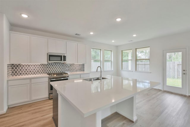 kitchen with sink, a center island with sink, white cabinets, and appliances with stainless steel finishes