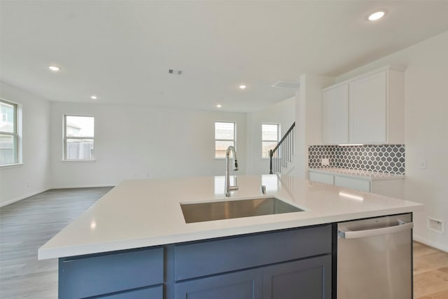 kitchen featuring dishwasher, sink, white cabinets, a kitchen island with sink, and light hardwood / wood-style floors