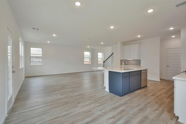 kitchen featuring a wealth of natural light, white cabinetry, an island with sink, decorative backsplash, and stainless steel dishwasher