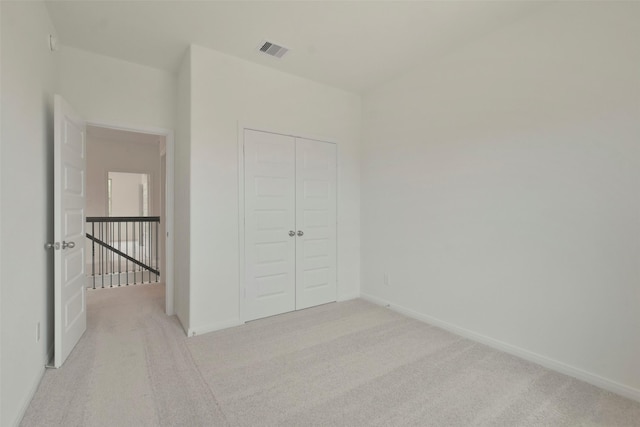 unfurnished bedroom with light colored carpet and a closet