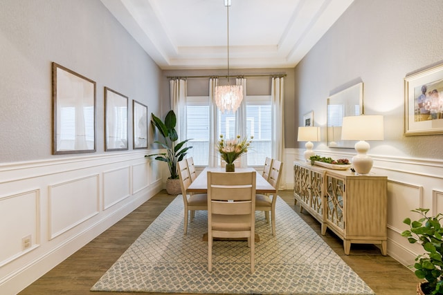 dining room featuring dark wood-type flooring, a tray ceiling, and an inviting chandelier