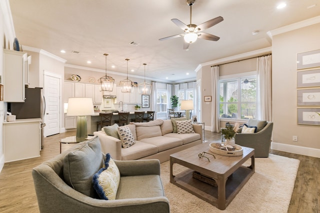 living room with crown molding, ceiling fan, sink, and light hardwood / wood-style floors