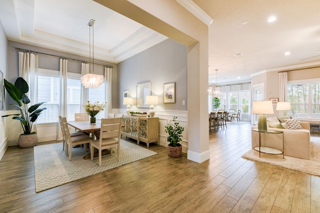 dining space with crown molding, a chandelier, and light hardwood / wood-style flooring