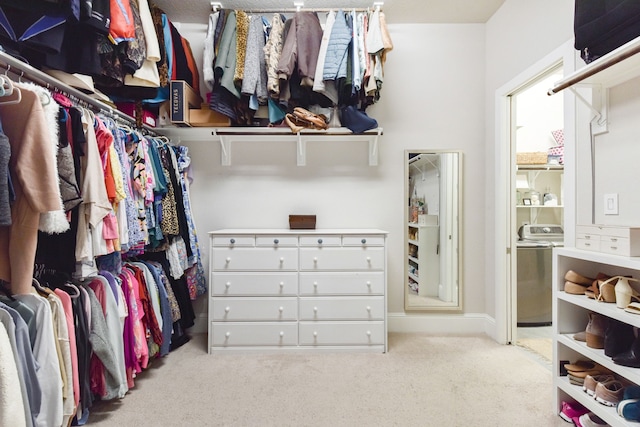 walk in closet featuring washer / dryer and light colored carpet