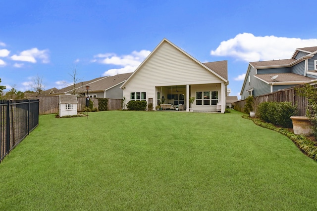 rear view of property with a storage unit and a lawn