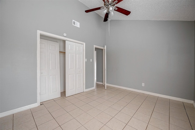 unfurnished bedroom with vaulted ceiling, a textured ceiling, light tile patterned floors, a closet, and ceiling fan