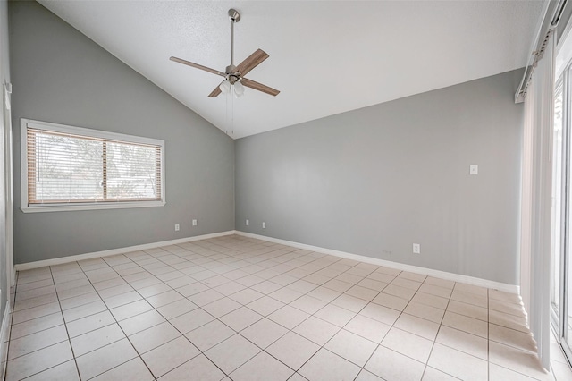 tiled empty room featuring ceiling fan, vaulted ceiling, and a wealth of natural light