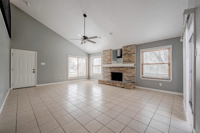 unfurnished living room featuring ceiling fan, high vaulted ceiling, a textured ceiling, light tile patterned flooring, and a brick fireplace