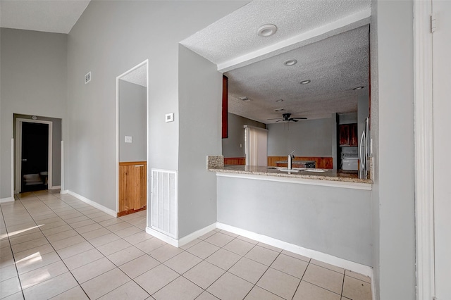 interior space with light tile patterned flooring, ceiling fan, sink, and a textured ceiling