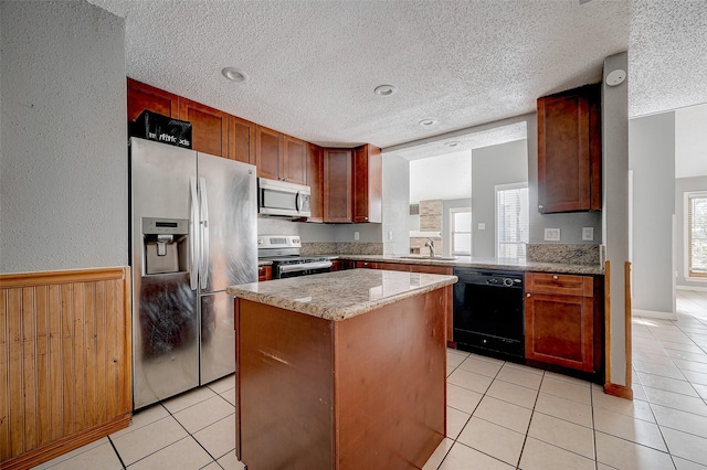 kitchen with appliances with stainless steel finishes, a center island, sink, and light tile patterned floors