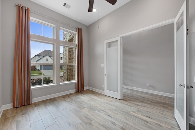 spare room with french doors, ceiling fan, a healthy amount of sunlight, and light hardwood / wood-style floors