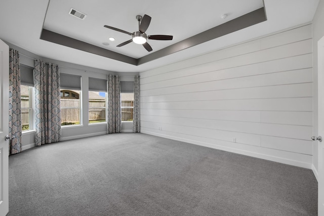 carpeted spare room featuring a raised ceiling and ceiling fan