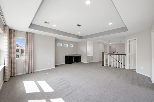 unfurnished living room featuring carpet floors and a raised ceiling