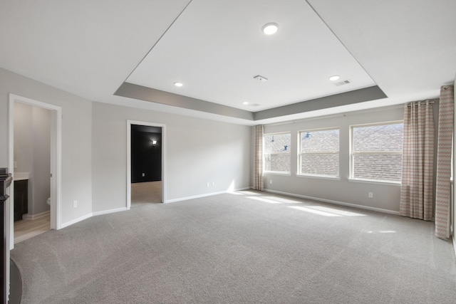 carpeted empty room with a raised ceiling