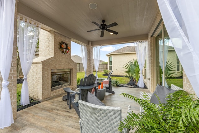 view of patio / terrace featuring an outdoor brick fireplace, a wooden deck, and ceiling fan