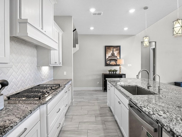 kitchen featuring sink, appliances with stainless steel finishes, pendant lighting, light stone countertops, and white cabinets