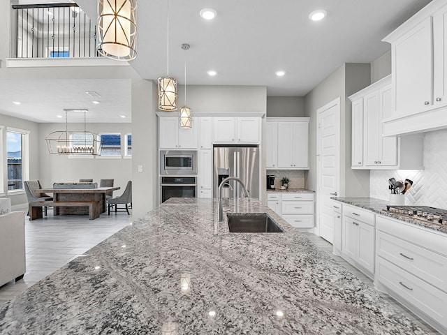 kitchen featuring pendant lighting, sink, appliances with stainless steel finishes, white cabinets, and stone countertops