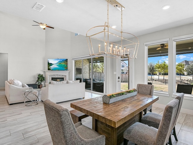 dining room with a towering ceiling, ceiling fan with notable chandelier, and light wood-type flooring