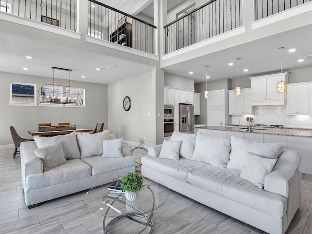 living room featuring sink, a chandelier, and a high ceiling