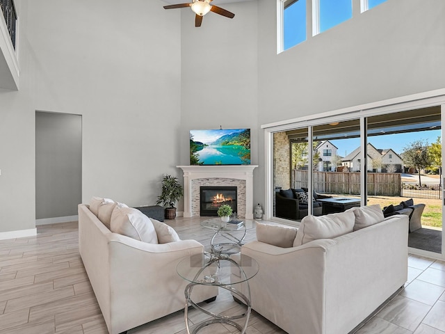 living room featuring a fireplace, ceiling fan, and light wood-type flooring