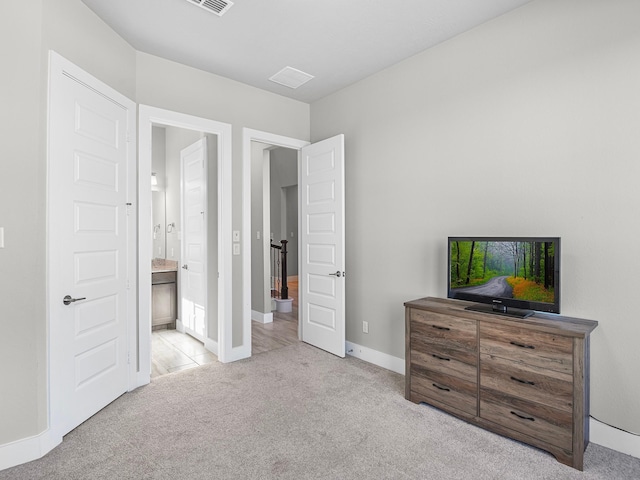 bedroom with ensuite bath and light carpet