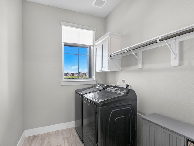 washroom with cabinets and washing machine and clothes dryer