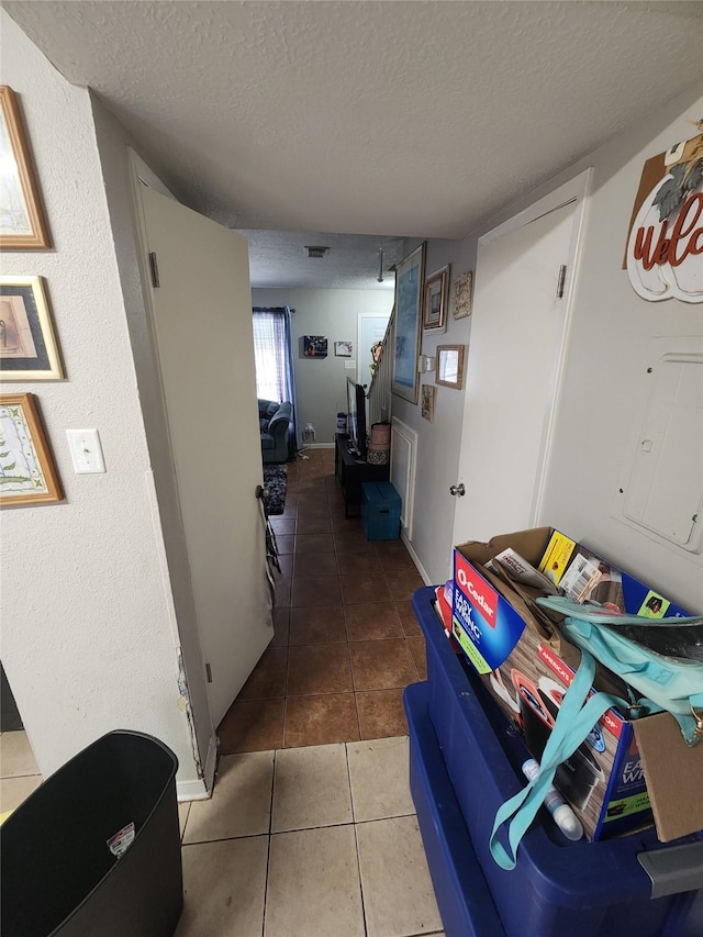 hallway with tile patterned floors and a textured ceiling