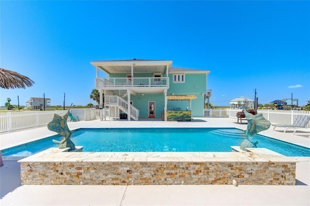 back of house with a fenced in pool, a balcony, and a patio area