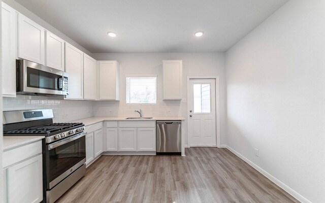 10791 Sora Dr, Willis, TX 77378 - kitchen featuring a sink, light wood finished floors, tasteful backsplash, and appliances with stainless steel finishes